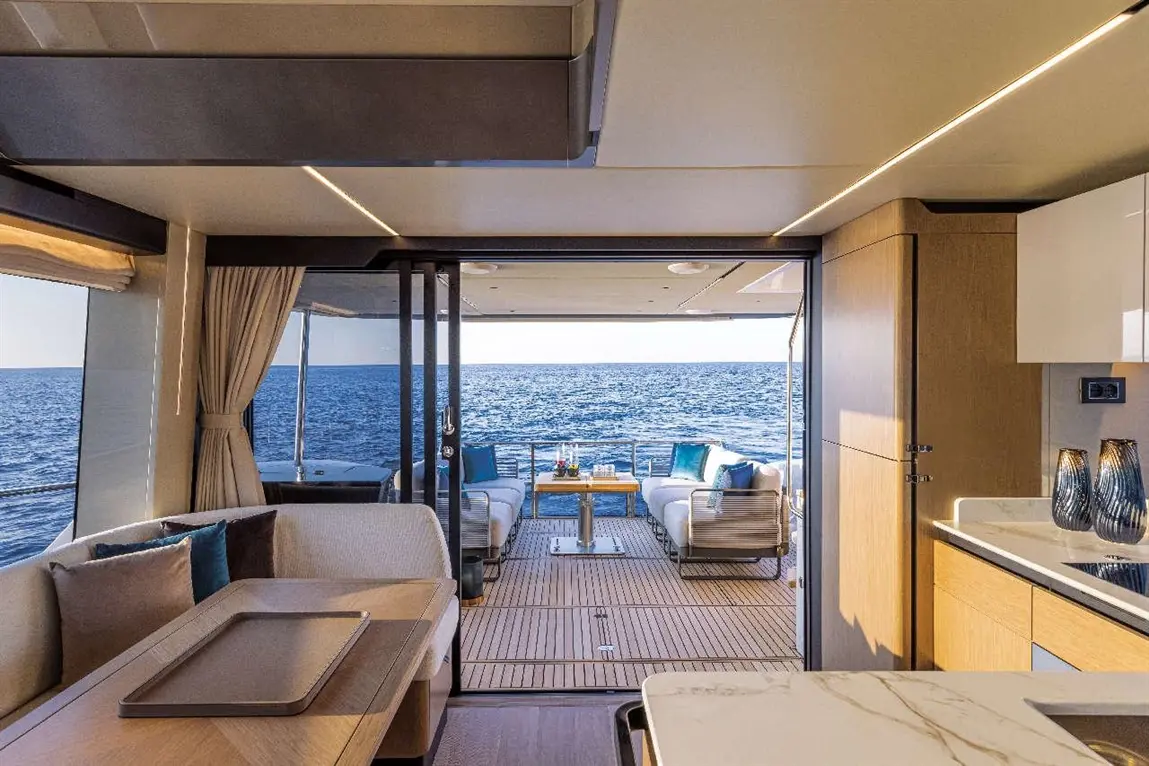 Stylish interior of a yacht with a view of the sea, featuring a dining area and cosy seating on the deck.